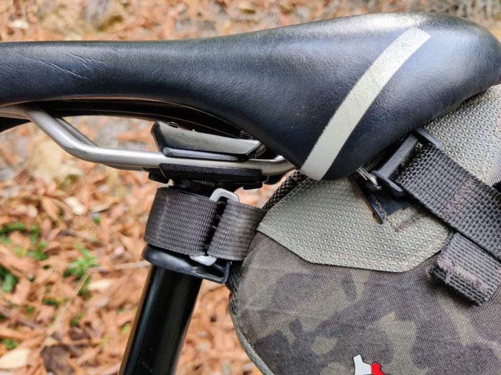 Close up of seat bag strap wrapped around Wolf Tooth Valais clamp on dropper post stanchion