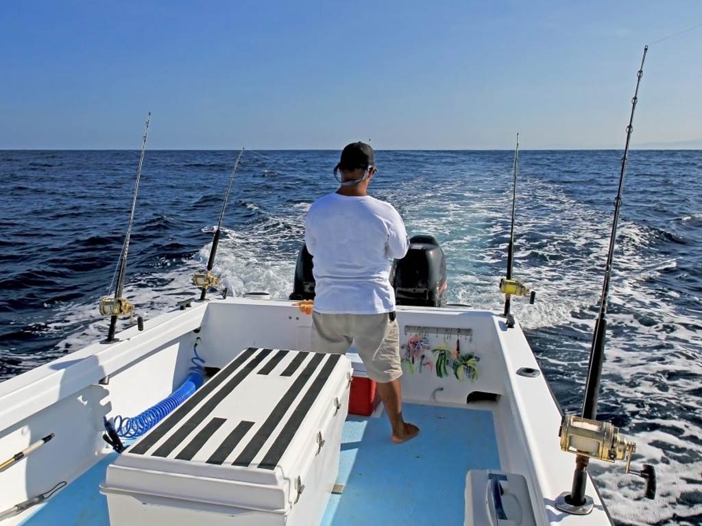 A photo featuring an angler standing on a charter boat while the boat is moving and trolling