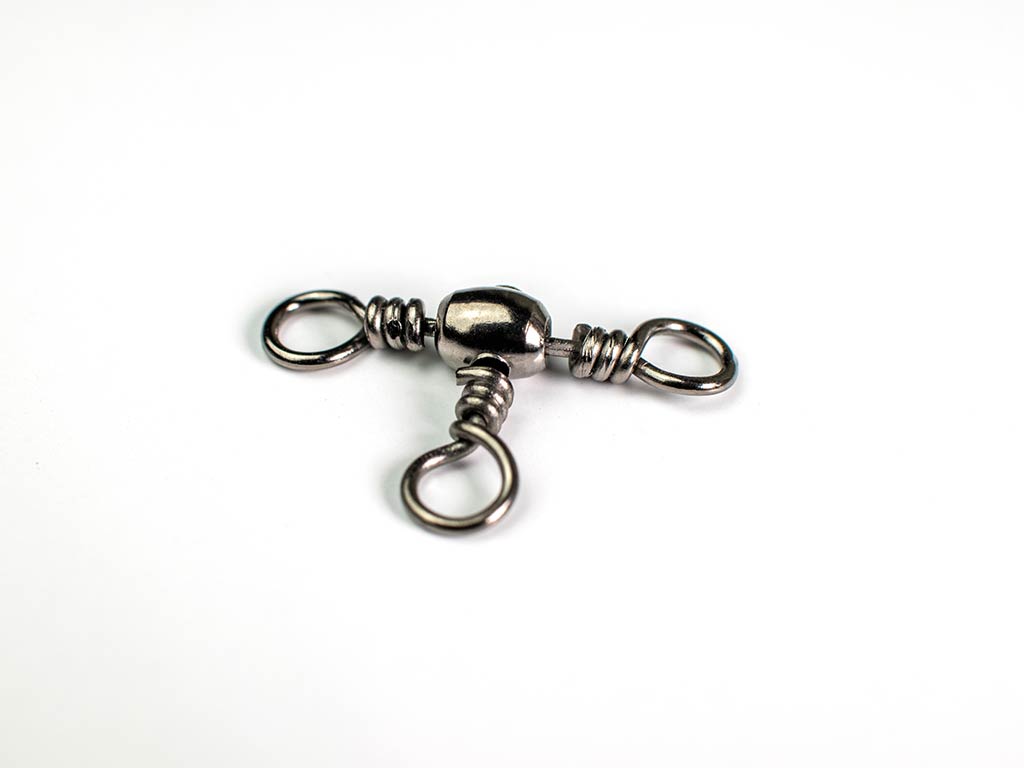 A closeup of a metal, three-way swivel used for fishing against a white background