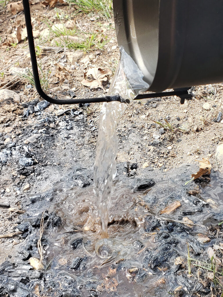 Photo of water being dumped on a campfire.