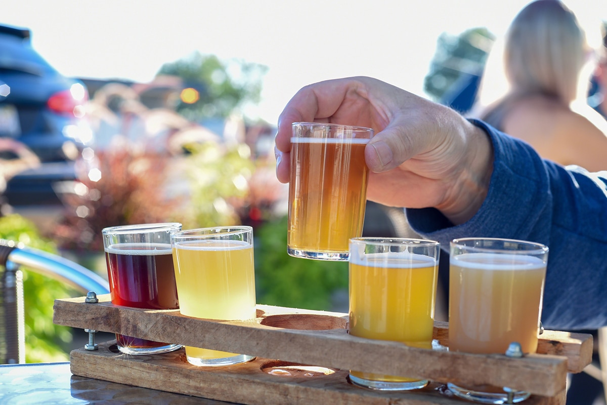 Man sampling a variety of seasonal craft beer at an outdoor beer garden, hands only